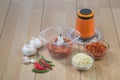 Food processor with chopped chilli and garlic on wooden table