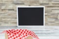 Food recipe template. Empty black board and picnic basket on a rustic wooden table over blurred stone wall background. For your Royalty Free Stock Photo