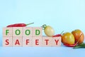 Food safety concept. Tomato and wooden blocks with word safe food on blue background with copy space. Royalty Free Stock Photo