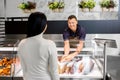 Seller showing seafood to customer at fish shop