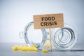 Board sign with text FOOD CRISIS and Remnants of pasta in glass jar