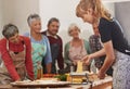 Food, senior cooking class and a woman teaching people in the kitchen of a home for meal preparation. Pasta maker Royalty Free Stock Photo