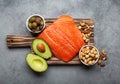 Food sources of healthy unsaturated fat: fresh raw salmon fillet, avocado, olives, nuts on cutting board, rustic stone Royalty Free Stock Photo