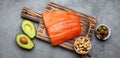 Food sources of healthy unsaturated fat: fresh raw salmon fillet, avocado, olives, nuts on cutting board, rustic stone Royalty Free Stock Photo