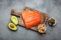 Food sources of healthy unsaturated fat: fresh raw salmon fillet, avocado, olives, nuts on cutting board, rustic stone Royalty Free Stock Photo