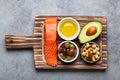 Food sources of healthy unsaturated fat: fresh raw salmon fillet, avocado, olives, nuts on cutting board, rustic stone Royalty Free Stock Photo