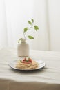 Food, spaghetti bolognese sauce in white dish and a vase of plants on a white prepared table Royalty Free Stock Photo