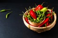 Food spices concept Assortment Chilli peppers in wicker bamboo tray on black slate stone board with copy space Royalty Free Stock Photo