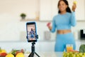 Food and sport vlog. Sporty black lady shooting video on smartphone, showing donut and apple, selective focus Royalty Free Stock Photo