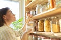 Food storage in pantry, woman holding jar of sugar in hand