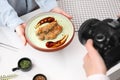 Food stylist holding plate with delicious meat medallion while photographer taking photo in studio, closeup Royalty Free Stock Photo