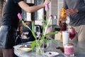 Food stylist and photographer decorate, preparing to shoot various cocktails, milkshakes, smoothies, flower tulips vase on table.