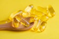 omega-3 and vitamin d fish oil pills in wooden spoon on yellow Royalty Free Stock Photo