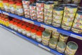 Various tinned foods and vegetables preserved in jars display on shelves in a supermarket,