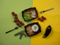 Food in takeaway box: rice with fish in sweet and sour sauce, chicken with buckwheat, vegetables and green salad.