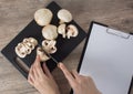 Food. To cook the champignon. Cut mushrooms with a knife on a black cutting Board. Write down the recipe. Copy space, clear space Royalty Free Stock Photo