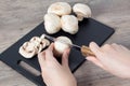 Food. To cook the champignon. Hand cuts mushrooms with a knife on a black cutting Board. Vegan, vegetarian. Top view, close-up Royalty Free Stock Photo