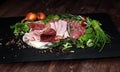 Food tray with delicious salami, pieces of sliced ham, sausage, tomatoes, salad and vegetable - Meat platter with selection Royalty Free Stock Photo