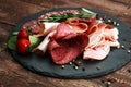 Food tray with delicious salami, pieces of sliced ham, sausage, tomatoes, salad and vegetable - Meat platter with selection Royalty Free Stock Photo