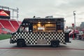 A food truck is parked in front of a busy stadium, serving delicious meals to hungry sports fans, Food truck with checkerboard Royalty Free Stock Photo