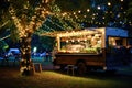 A food truck is parked under a tree that is adorned with beautiful lights, A food truck with twinkling fairy lights at a summer