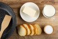 Food turner in frying pan, butter, jug of milk, bread, salt on wooden table. Top view Royalty Free Stock Photo