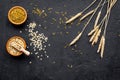 Food which rich with slow carbohydrates. Oatmeal and oat in bowls near sprigs of wheat on black background top view copy Royalty Free Stock Photo