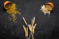 Food which rich with slow carbohydrates. Oatmeal and oat in bowls near sprigs of wheat on black background top view copy Royalty Free Stock Photo