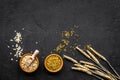 Food which rich with slow carbohydrates. Oatmeal and oat in bowls near sprigs of wheat on black background top view copy Royalty Free Stock Photo