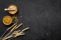 Food which rich with slow carbohydrates. Oatmeal and oat in bowls near sprigs of wheat on black background top view copy Royalty Free Stock Photo