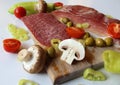 Food - wooden cutting board with slices of salami and ham, olives, mushrooms and cut tomatoes and green peppers Royalty Free Stock Photo