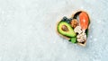 Foods good for the heart: nuts, salmon, avocados, spinach, mushrooms, berries. In a heart-shaped box. On a stone background.