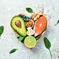 Foods good for the heart: nuts, salmon, avocados, spinach, mushrooms, berries. In a heart-shaped box. On a stone background.