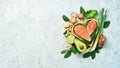 Foods good for the heart: nuts, salmon, avocados, spinach, mushrooms, berries. In a heart-shaped box. On a stone background.