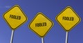 Fooled - three yellow signs with blue sky background