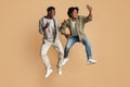 Fooling Together. Two Black Guys Taking Selfie While Jumping Over Beige Background Royalty Free Stock Photo