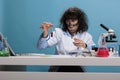 Foolish crazy looking mad chemist sitting at desk in laboratory while experiment with new chemical compounds after lab