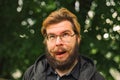 Foolish portrait funny grimace male face photography of middle adult bearded person in glasses outside park outdoor space