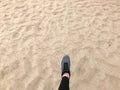 The foot in the gray boot shoe makes a step against the background of a natural loose yellow golden beautiful warm beach sand Royalty Free Stock Photo
