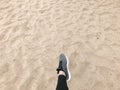 The foot in the gray boot shoe makes a step against the background of a natural loose yellow golden beautiful warm beach sand Royalty Free Stock Photo