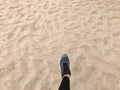 The foot in the gray boot shoe makes a step against the background of a natural loose yellow golden beautiful warm beach sand Royalty Free Stock Photo