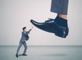 Foot of leader or boss with authority huge trample on frightened employee with bullying, businessman in suite strong and defense. Royalty Free Stock Photo