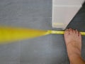 A foot of a man holding / stepping on a bended measuring tape checking the length and height of a counter - skill in using a