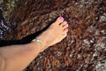 Foot with pink enamel on reddish stone Royalty Free Stock Photo