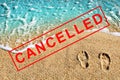 Foot prints on beach sand, blue sea wave landscape, red CANCELLED stamp, Coronavirus pandemic, covid 19 epidemic, cancellation Royalty Free Stock Photo