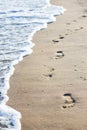 Foot prints at beach sand. White bright wave, sea foam Royalty Free Stock Photo