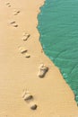 Foot steps and surf on tropical beach Royalty Free Stock Photo