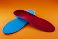 Foot support and healthy feet concept with orthopedic shoe insoles isolated on orange background