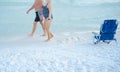 Foot view of senior couple in bikini and short walking along white sandy shore near reclining backpack beach chair, Destin beach, Royalty Free Stock Photo