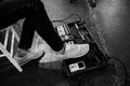 Foot wearing New Balance sneakers pressing on effects units for guitar on concert stage Royalty Free Stock Photo